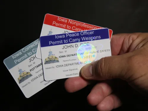 A hand holding 3 weapon permit cards