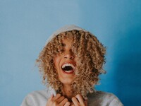 Woman with gray hoodie smiling with big open mouth